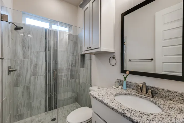 a bathroom with a granite countertop sink toilet and shower