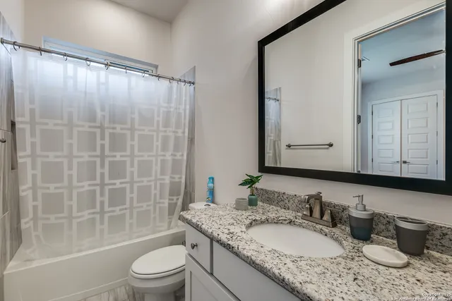 a bathroom with a granite countertop bathtub sink vanity mirror and toilet
