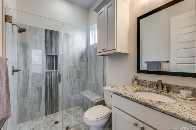 a bathroom with a granite countertop sink toilet and shower