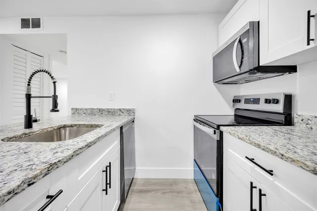 a kitchen with granite countertop stainless steel appliances granite countertop a sink and a stove