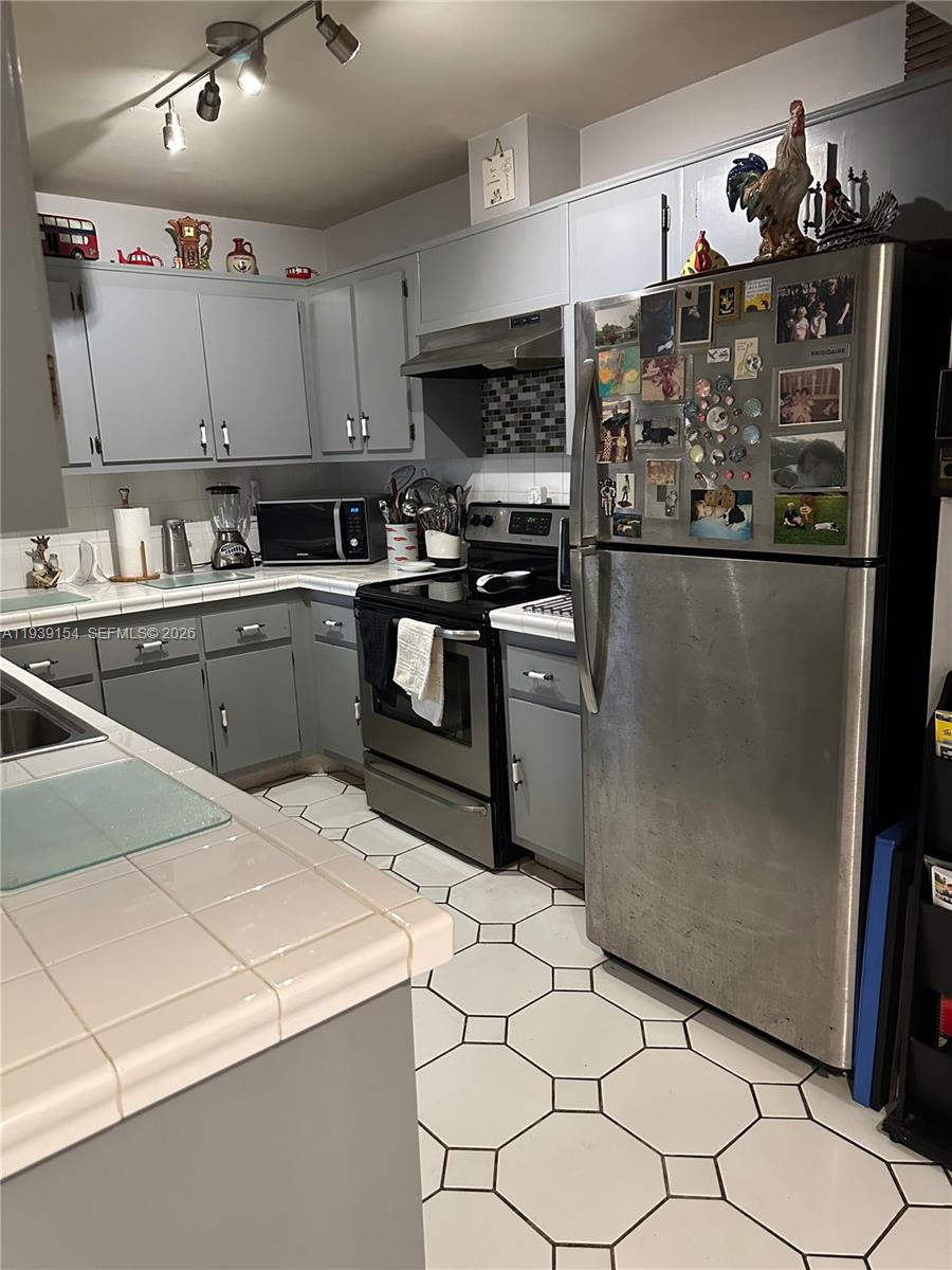 11438 Southwest 86th Lane Miami, FL 33173 - Photo 10 of 17 a kitchen with stainless steel appliances kitchen island granite countertop a refrigerator and a stove top oven