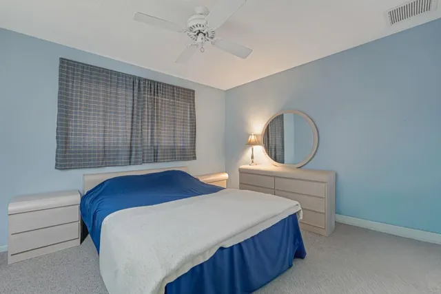 a bedroom with a bed a dresser and windows