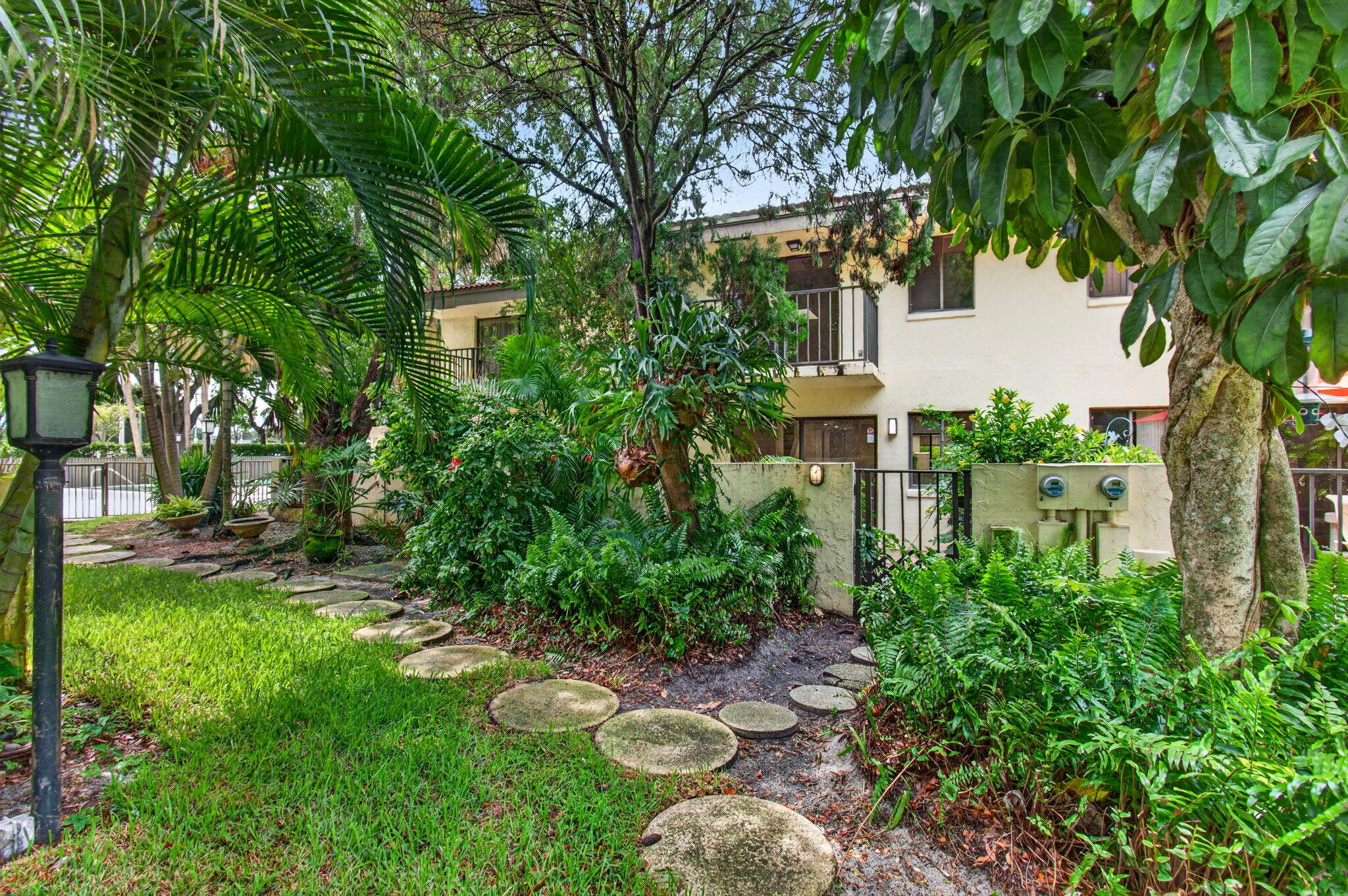 1330 Northwest 13th Street, Unit 12 Boca Raton, FL 33486 - Photo 48 of 52 a view of backyard with table and chairs and potted plants and large trees