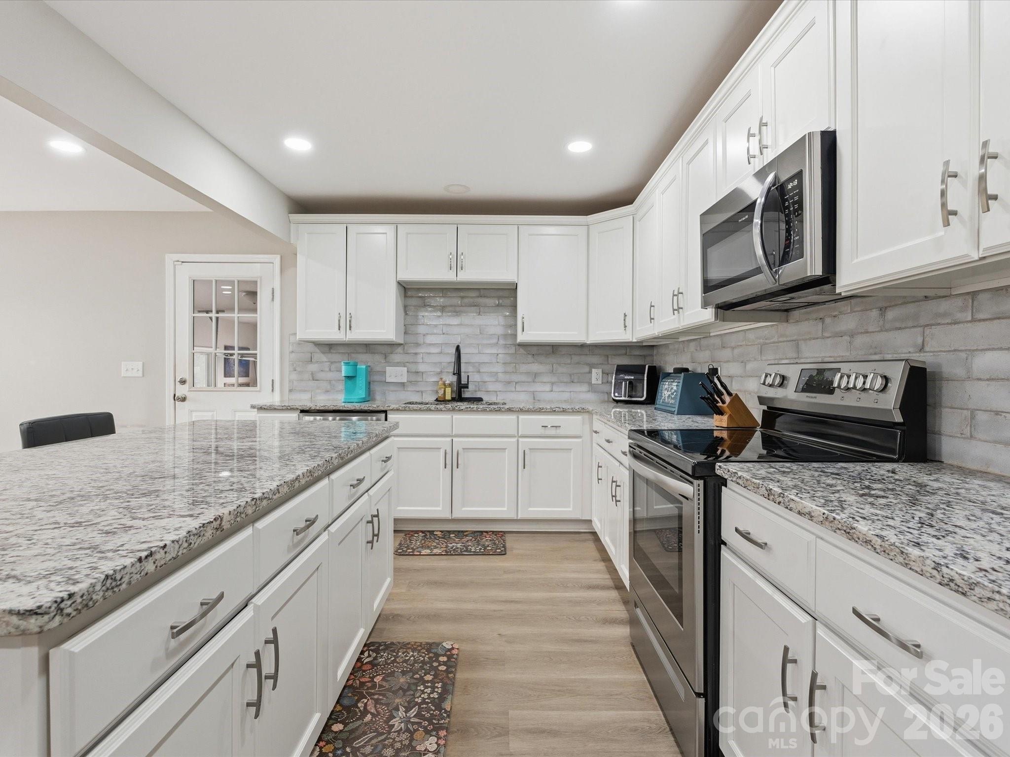 1804 Highway 161, Unit 1 Clover, SC 29710 - Photo 14 of 46 a large kitchen with stainless steel appliances granite countertop a stove top oven a sink dishwasher a microwave oven and a granite counter tops with wooden floors