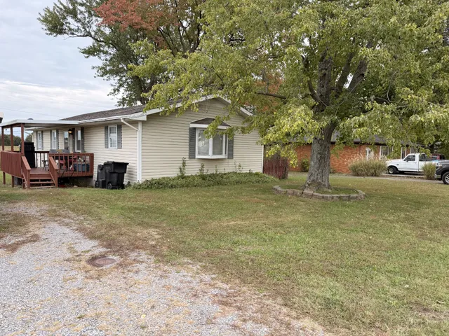 a front view of a house with a garden and tree