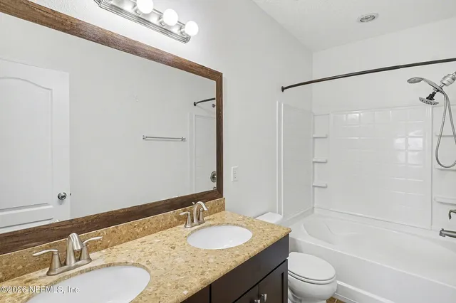 a bathroom with a granite countertop sink toilet mirror and shower