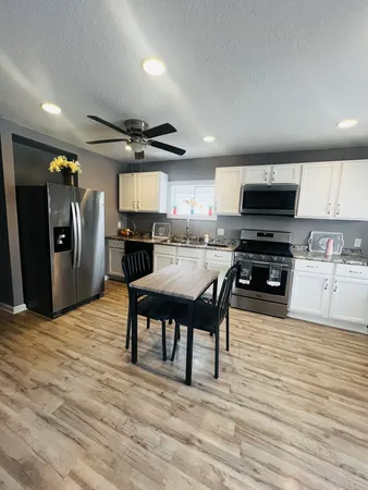 a kitchen with stainless steel appliances kitchen island granite countertop a refrigerator a sink a stove and a microwave with wooden floor