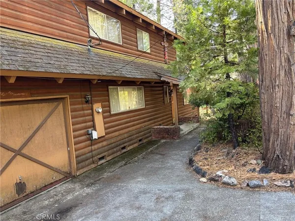 a view of a house with a yard and large tree