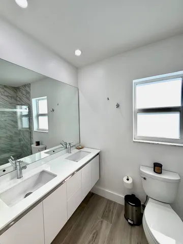a bathroom with a double vanity sink toilet and mirror