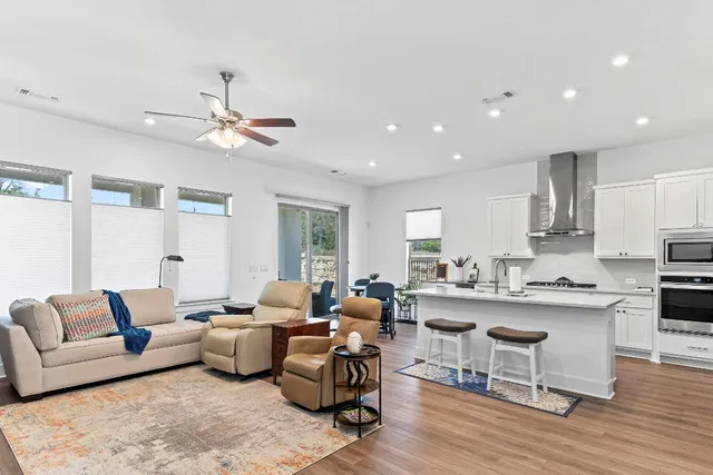 a living room with furniture kitchen view and a wooden floor
