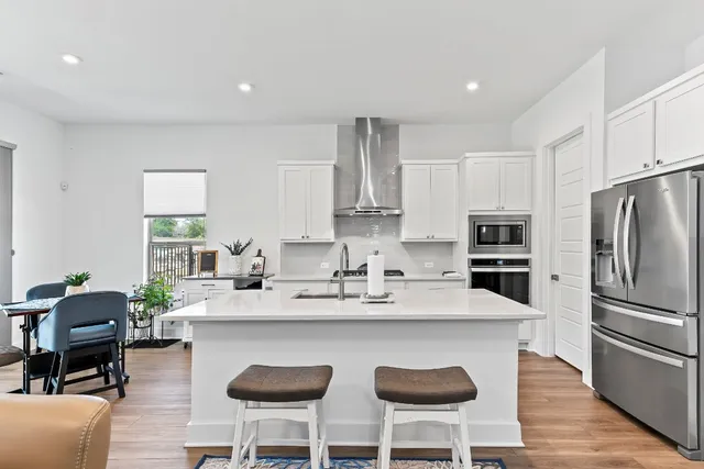 a kitchen with stainless steel appliances granite countertop a table chairs refrigerator and sink