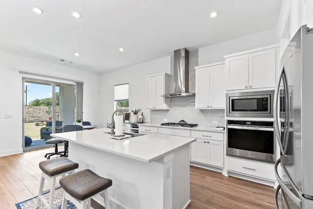 a kitchen with stainless steel appliances kitchen island granite countertop a sink a stove a microwave a counter space and cabinets