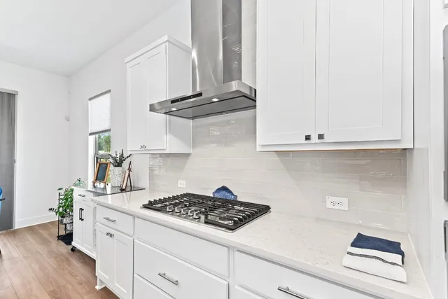 a kitchen with stainless steel appliances a stove and white cabinets