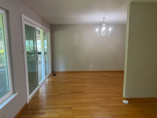 a view of an empty room with wooden floor and a carpet