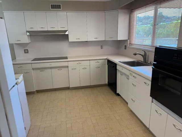 a kitchen with cabinets appliances a sink and a window
