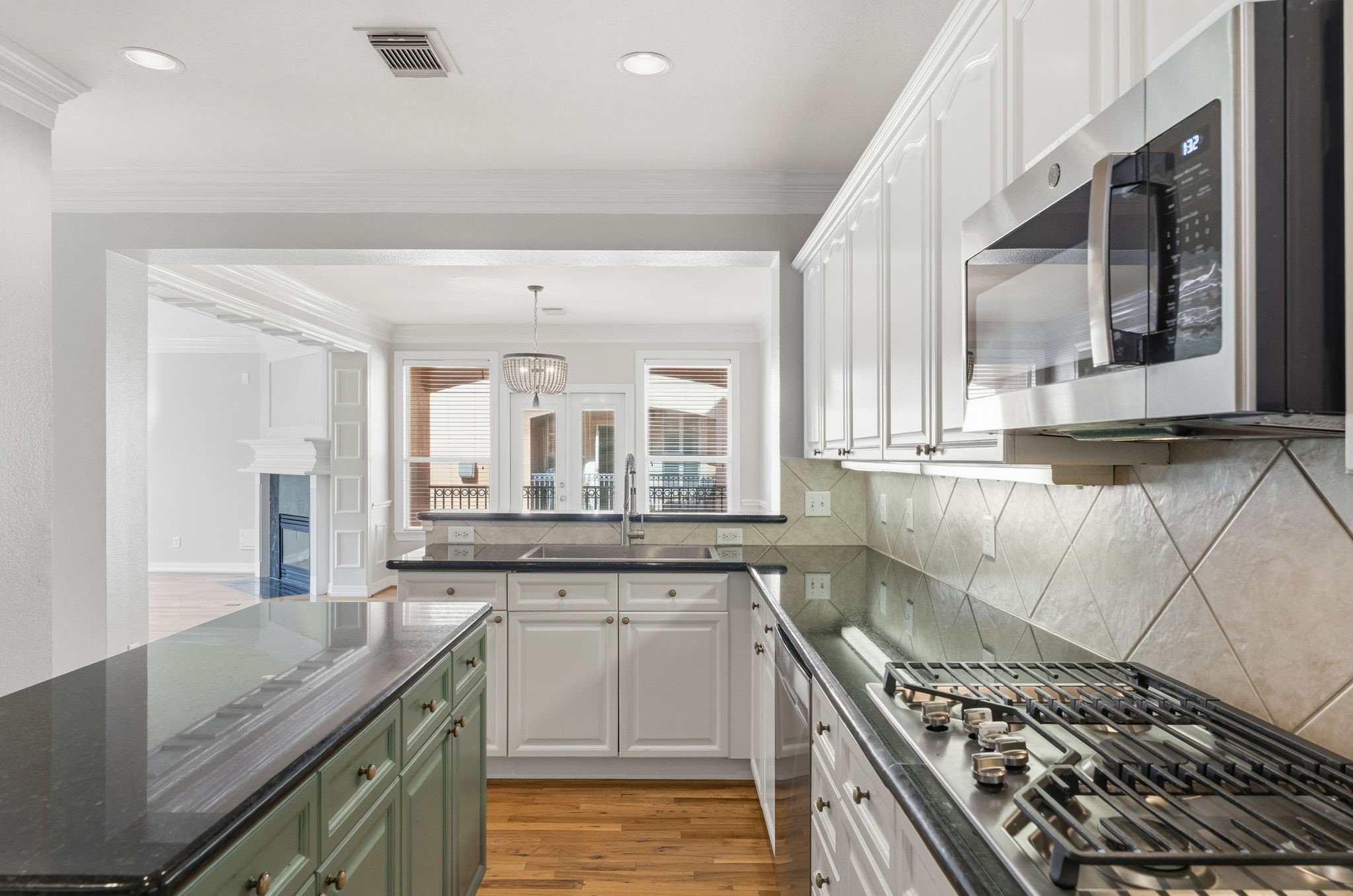 827 Rosine Street Houston, TX 77019 - Photo 18 of 50 Modern kitchen featuring stainless steel appliances, granite countertops, and ample cabinet space. Opens to a bright dining area with a view of the living room, showcasing a fireplace and elegant lighting.