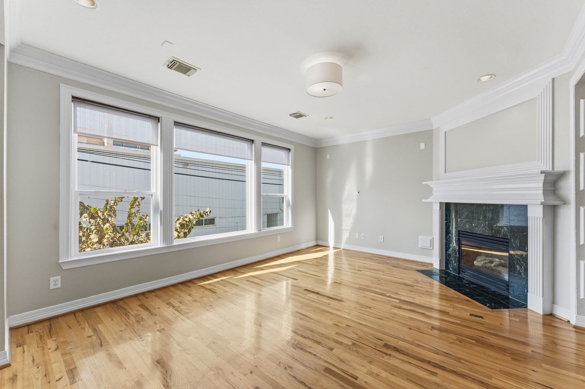 827 Rosine Street Houston, TX 77019 - Photo 20 of 50 This bright, spacious living room features large windows, hardwood floors, and a cozy fireplace, offering an inviting and elegant space for relaxation and entertaining.