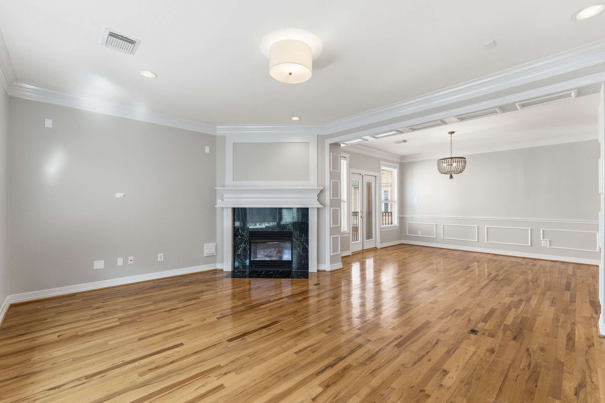827 Rosine Street Houston, TX 77019 - Photo 23 of 50 This spacious living area features elegant hardwood floors, a cozy fireplace, and ample natural light. The open layout seamlessly connects to a dining space with a stylish chandelier, perfect for entertaining.