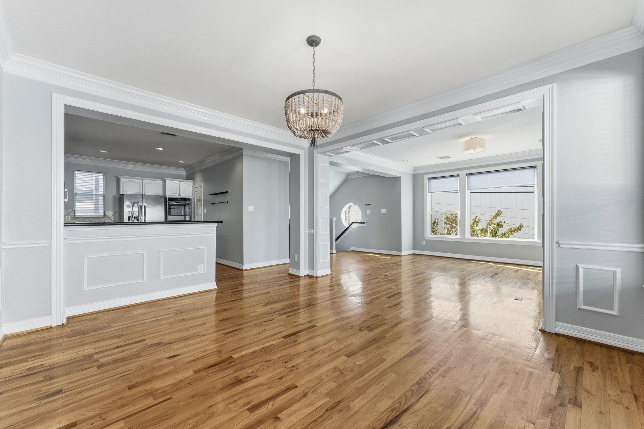 827 Rosine Street Houston, TX 77019 - Photo 26 of 50 This bright, open-concept living space features hardwood floors, elegant crown molding, and a stylish chandelier. The area flows seamlessly into a modern kitchen with stainless steel appliances, offering a perfect blend of sophistication and functionality. Large windows provide abundant natural light.