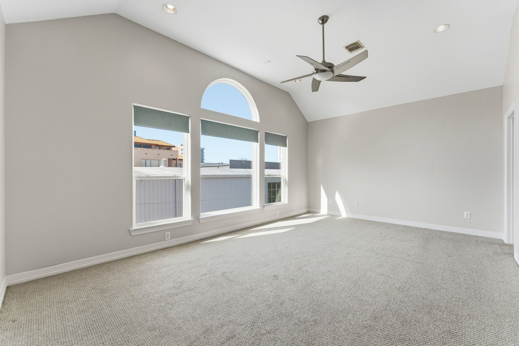 827 Rosine Street Houston, TX 77019 - Photo 35 of 50 This bright, spacious room features vaulted ceilings and large, arched windows that allow plenty of natural light. It has neutral carpeting and a modern ceiling fan, creating a comfortable and inviting space.