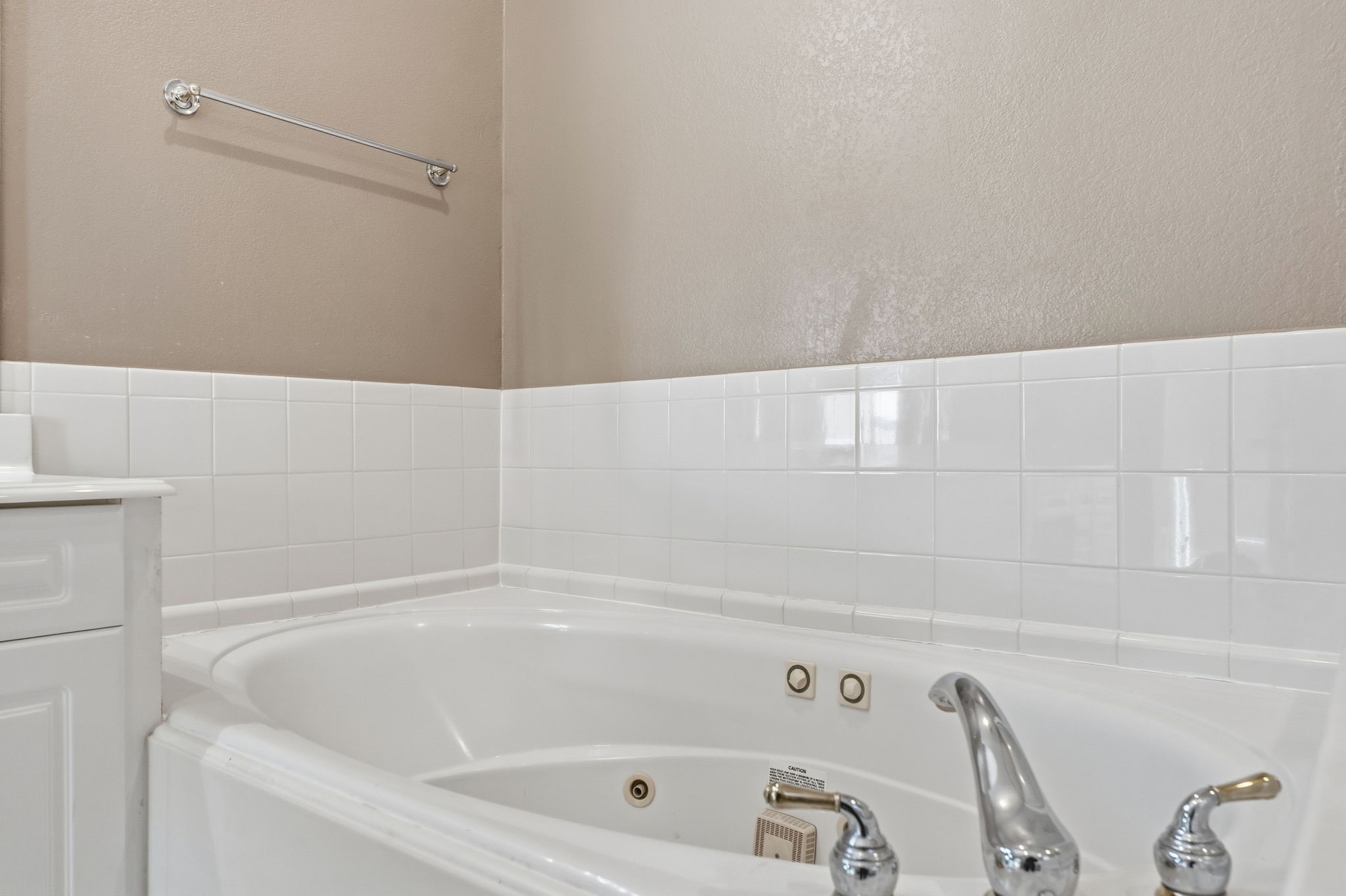 827 Rosine Street Houston, TX 77019 - Photo 41 of 50 This bathroom features a cozy corner bathtub with sleek chrome fixtures, surrounded by white tile and neutral walls, creating a relaxing atmosphere.