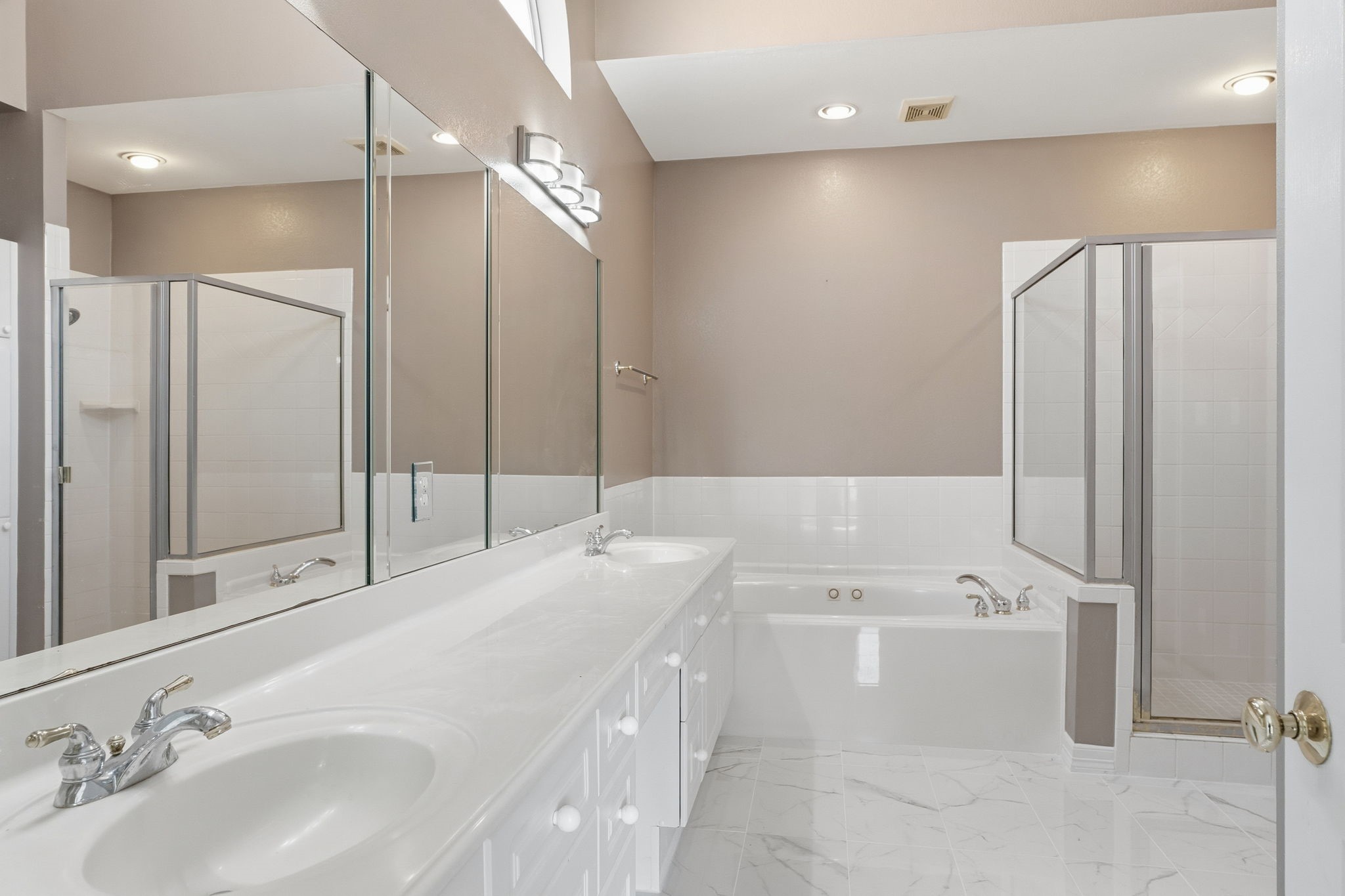 827 Rosine Street Houston, TX 77019 - Photo 43 of 50 This bathroom features a modern design with dual sinks, a large mirror, and a spacious walk-in shower. It includes a separate bathtub and elegant tile flooring, creating a bright and inviting atmosphere.