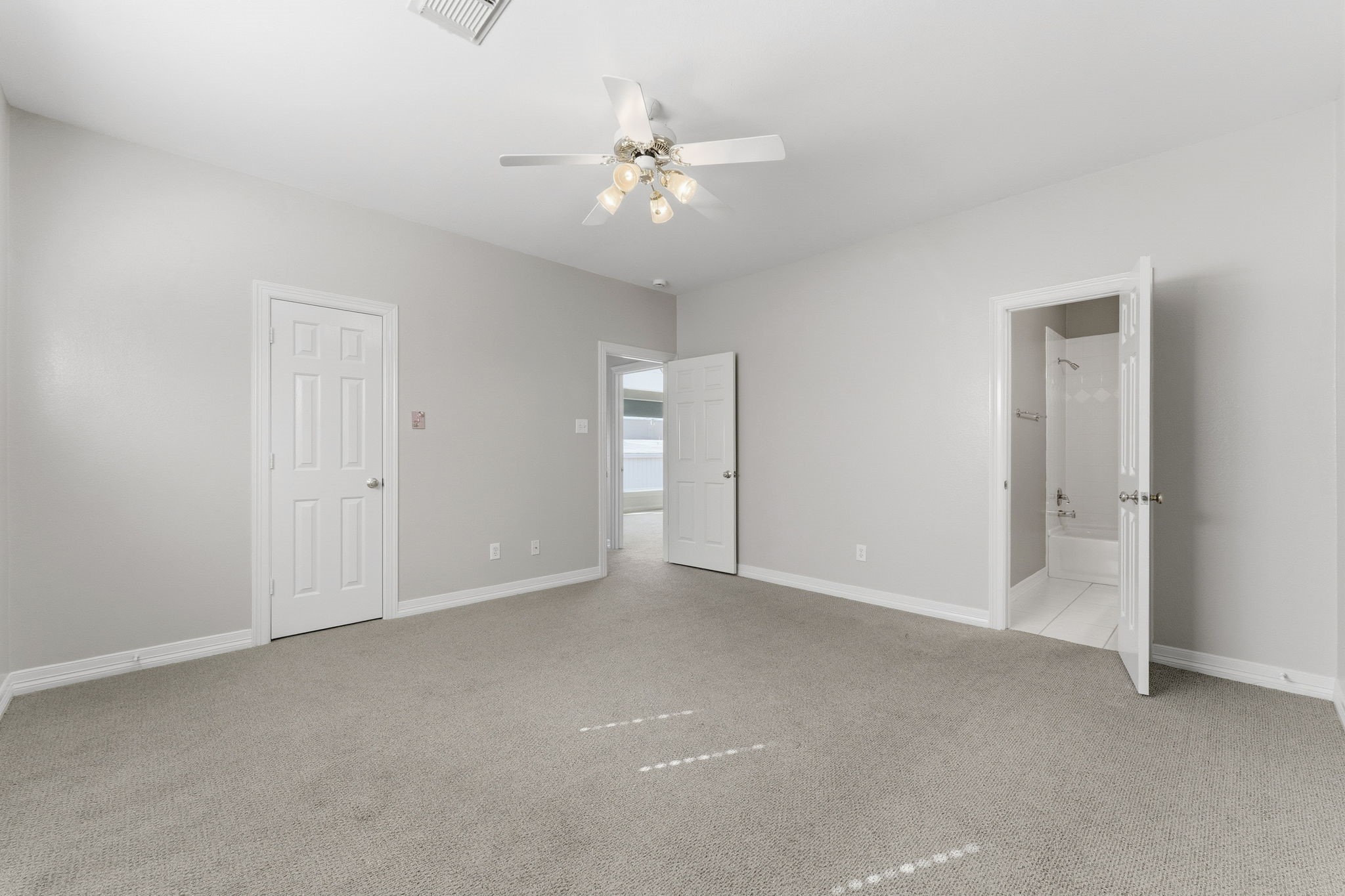 827 Rosine Street Houston, TX 77019 - Photo 47 of 50 This room features neutral carpeting, soft gray walls, and a ceiling fan for comfort. It includes two doors leading to a bathroom and an adjacent room, offering convenience and privacy.