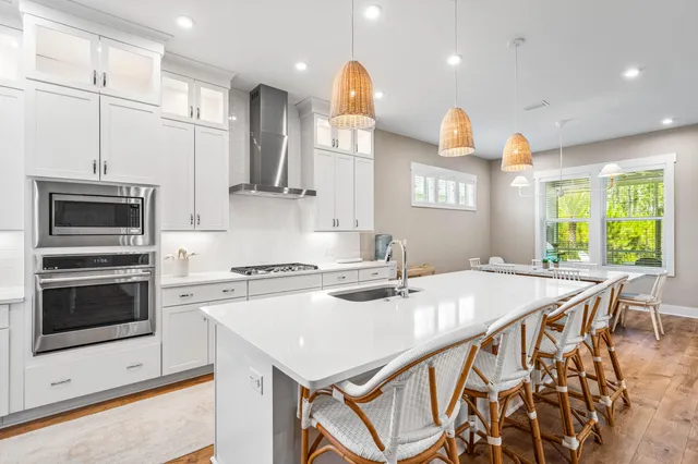 a kitchen with a stove a sink a kitchen island with a dining table and chairs