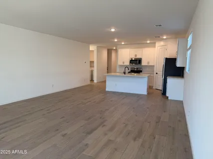 a view of a kitchen with cabinets stainless steel appliances wooden floor and a sink