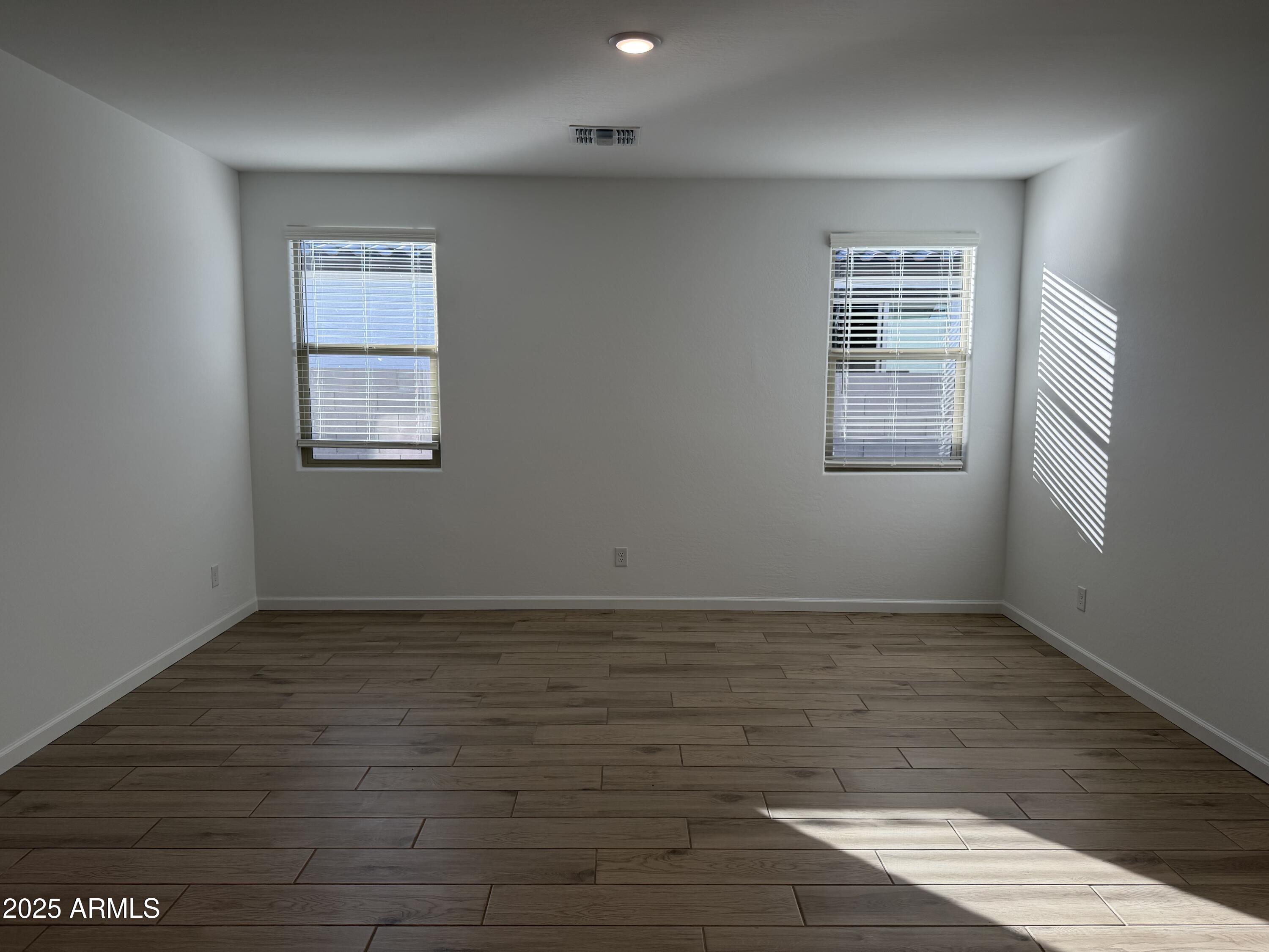 5533 West Buist Avenue Laveen, AZ 85339 - Photo 23 of 42 an empty room with wooden floor and windows