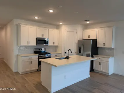 a kitchen with a sink a stove a refrigerator a center island and a window