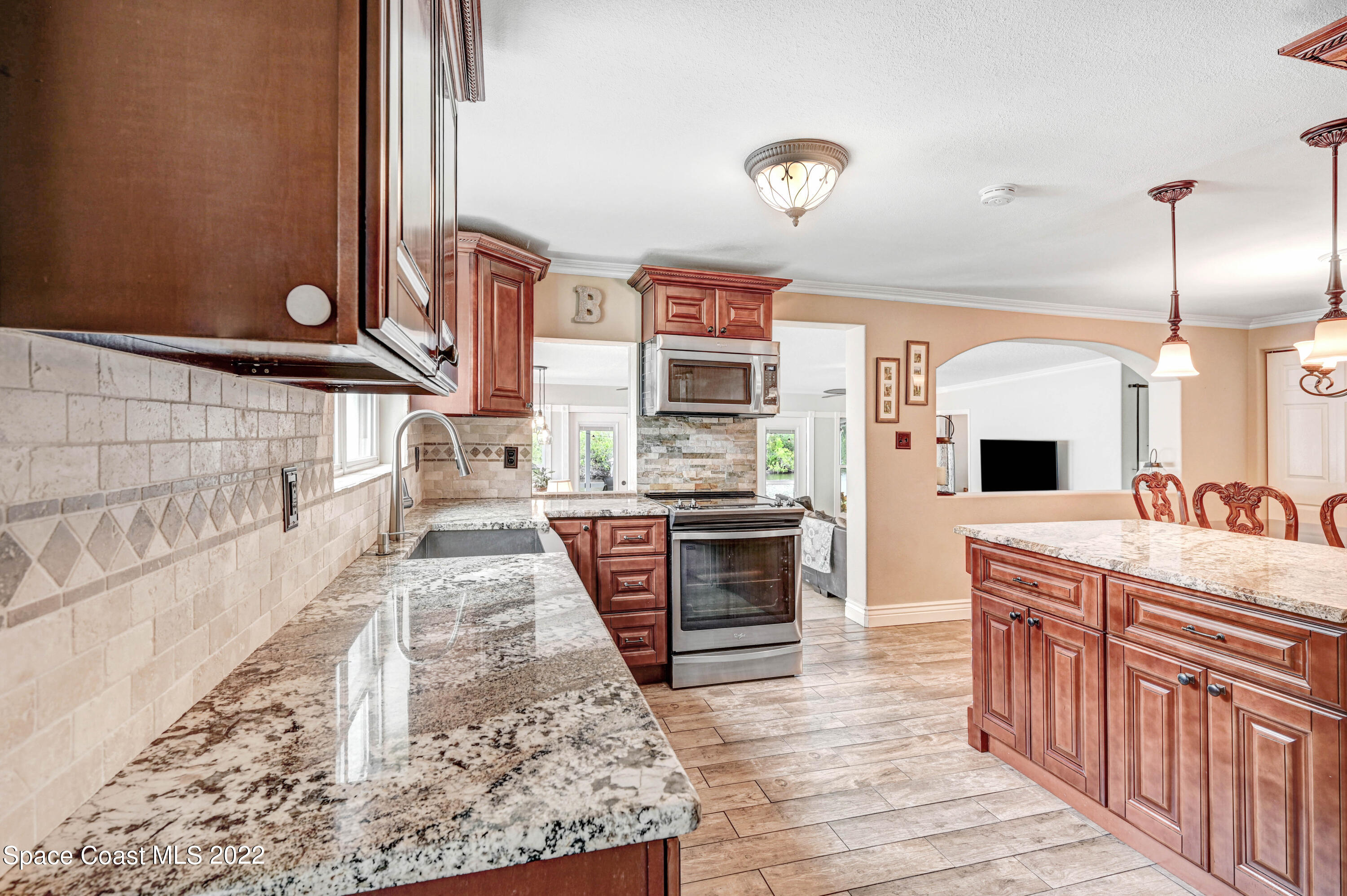 1304 Lichty Street Palm Bay, FL 32905 - Photo 7 of 57 a large kitchen with stainless steel appliances granite countertop a stove and a wooden cabinets