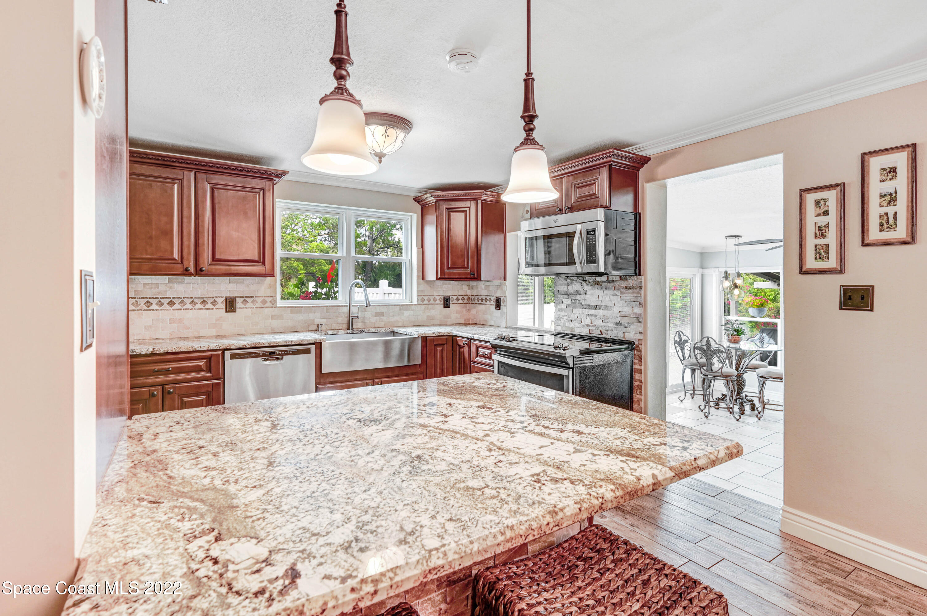 1304 Lichty Street Palm Bay, FL 32905 - Photo 8 of 57 a kitchen with stainless steel appliances granite countertop a stove top oven a sink dishwasher a dining table and chairs with wooden floor