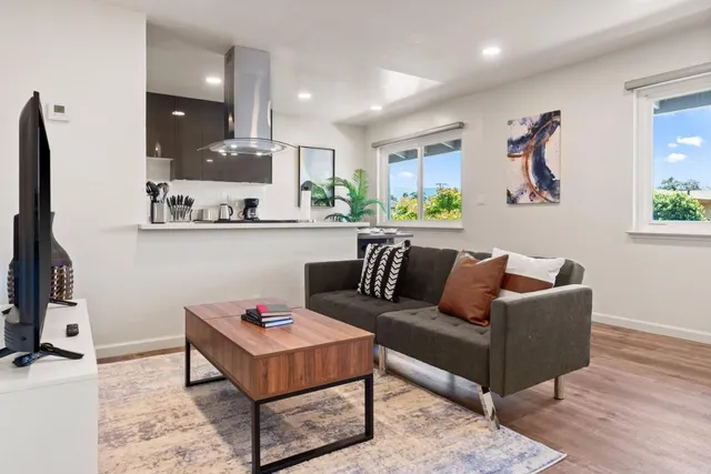 a living room with furniture a rug kitchen view and a window