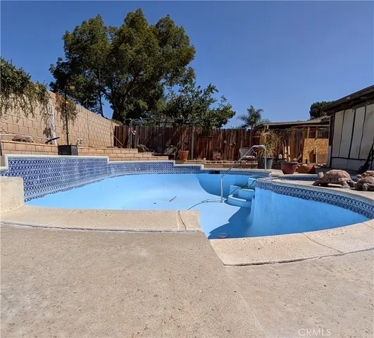 a view of swimming pool with outdoor seating and a tree in the background