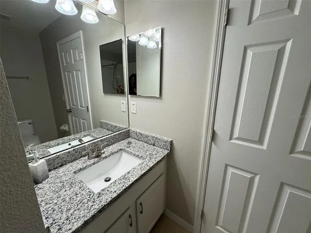 a bathroom with a granite countertop sink and a mirror