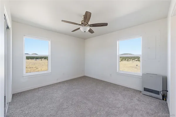 an empty room with windows and ceiling fan