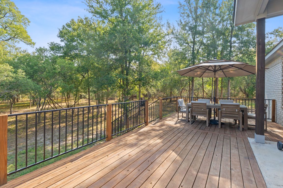159 Raptor Beak Way Cedar Creek, TX 78612 - Photo 27 of 31 a view of a roof deck with table and chairs under an umbrella with wooden floor and fence