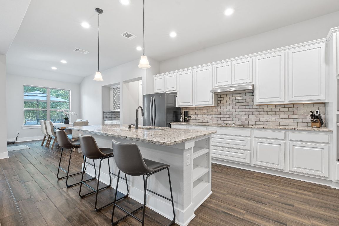159 Raptor Beak Way Cedar Creek, TX 78612 - Photo 4 of 31 a kitchen with stainless steel appliances granite countertop a stove a sink a kitchen island with a dining table and chairs