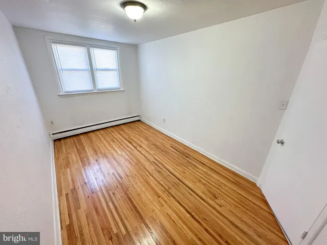 an empty room with wooden floor cabinet and windows