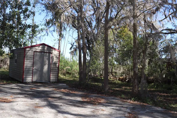 a view of a barn with a yard and large trees