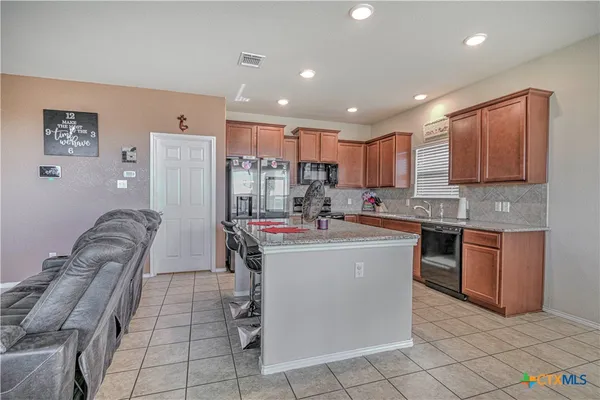 a kitchen with kitchen island granite countertop lots of white cabinets a sink and a stove