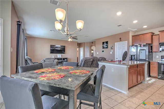 a kitchen island with stainless steel appliances kitchen island granite countertop a table chairs and a refrigerator