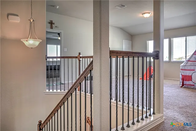 a view of staircase with lots of frames on wall and a large window