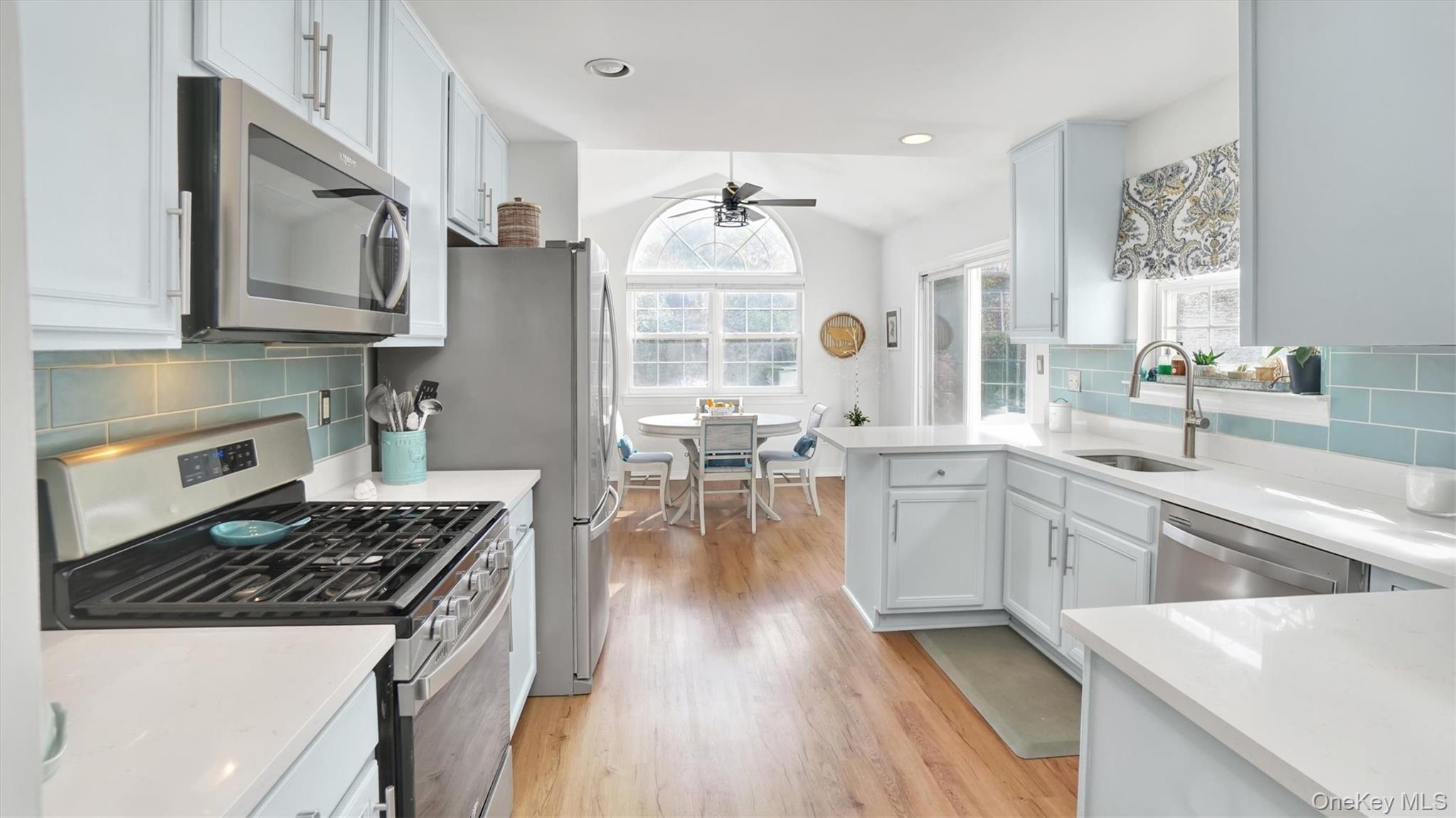 601 Pebble Beach Path Riverhead, NY 11901 - Photo 8 of 20 a kitchen with a stove a sink dishwasher a microwave oven and a dining table with wooden floor