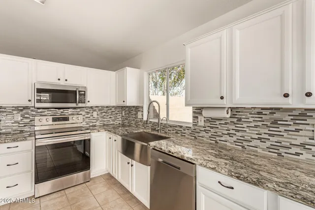 a kitchen with granite countertop white cabinets and white appliances