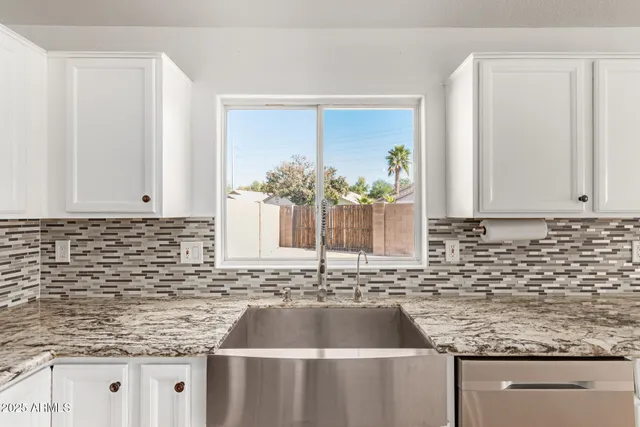 a kitchen with granite countertop a sink and a white cabinets