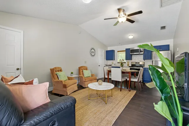 a living room with furniture kitchen view and a chandelier