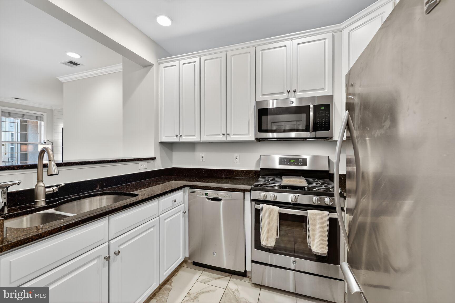 2330 14th Street North, Unit 205 Arlington, VA 22201 - Photo 4 of 29 a kitchen with granite countertop white cabinets and stainless steel appliances