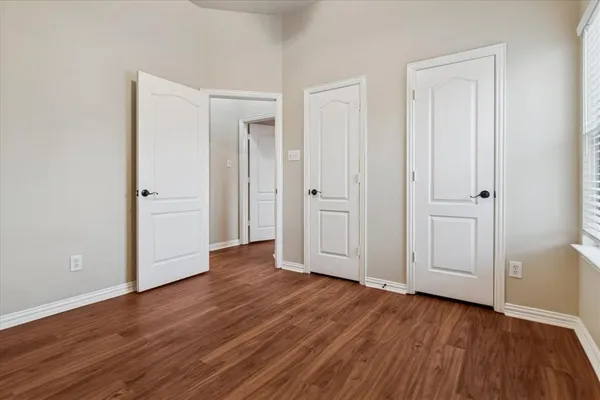an empty room with wooden floor and closet area